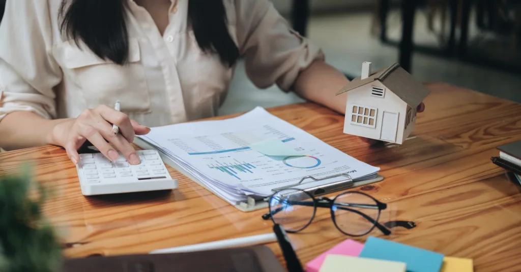 businesswoman with house model doing finances and calculate about cost to real estate investment